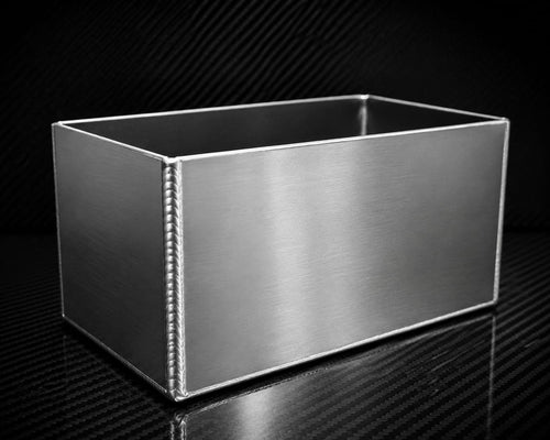 Custom fabricated aluminium battery box with TIG welded seams on carbon fibre surface